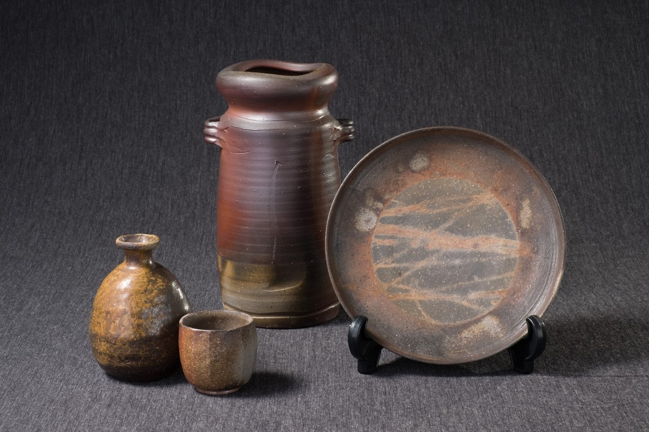 A Bizen flower vase, sake flask, cup, and plate arranged together