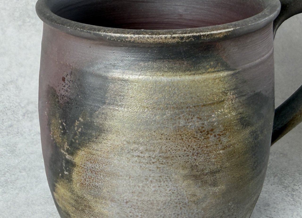Close-up of unglazed Bizen clay, matte in places with a soft sheen where wood ash melted