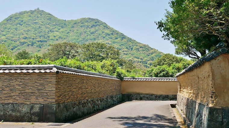 A stone castle wall in Hagi with a wooded mountain rising behind it
