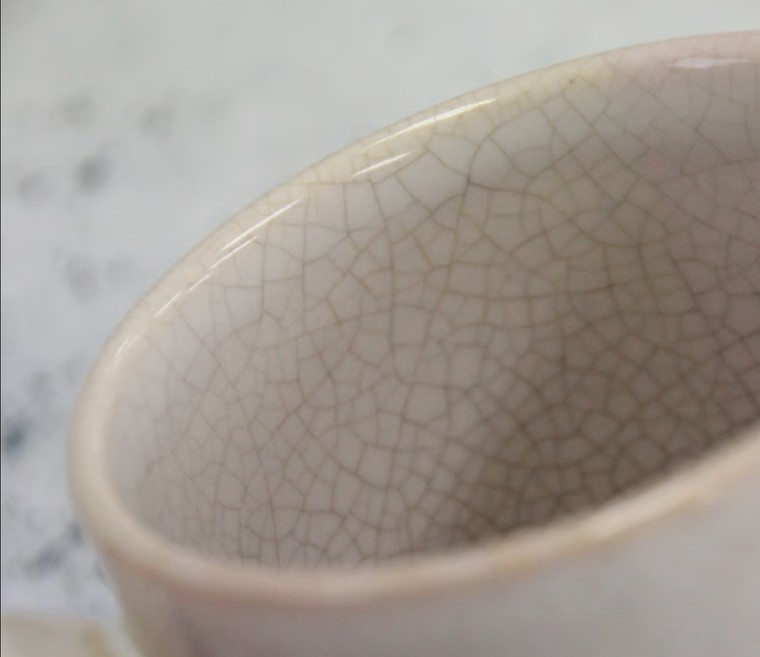 A close view of the fine crackle network inside a Hagi-ware bowl, the pathway through which tea or sake slowly changes the piece's color