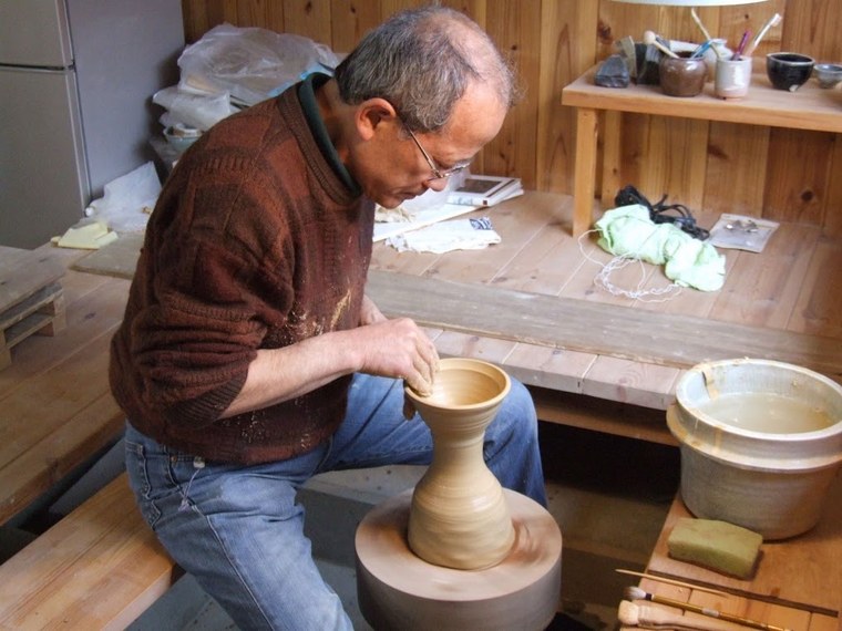 A potter shaping a piece of Hagi ware by hand on a pottery wheel