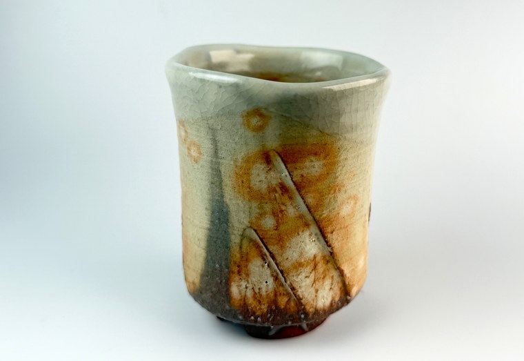 A close view of a Hagi-ware teacup showing the fine crackle in its glaze and the soft color shift across its surface