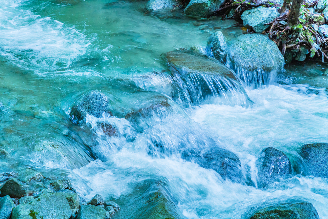 A Japanese mountain stream — turquoise water tumbling over moss-covered rocks, the shapeless flow that the painter then gives form to