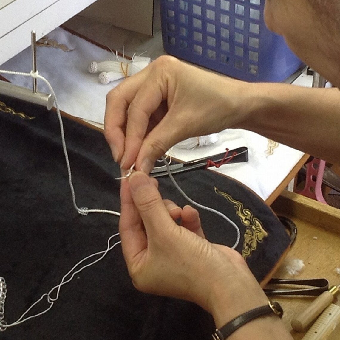 A Kyoto craftsperson threading juzu beads onto silk thread by hand