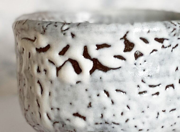 Close view of a white Hagi glaze drawn back into raised, pebbled islands, with dark clay showing between them