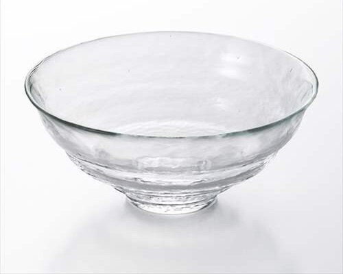 A wide, clear glass tea bowl on a white background