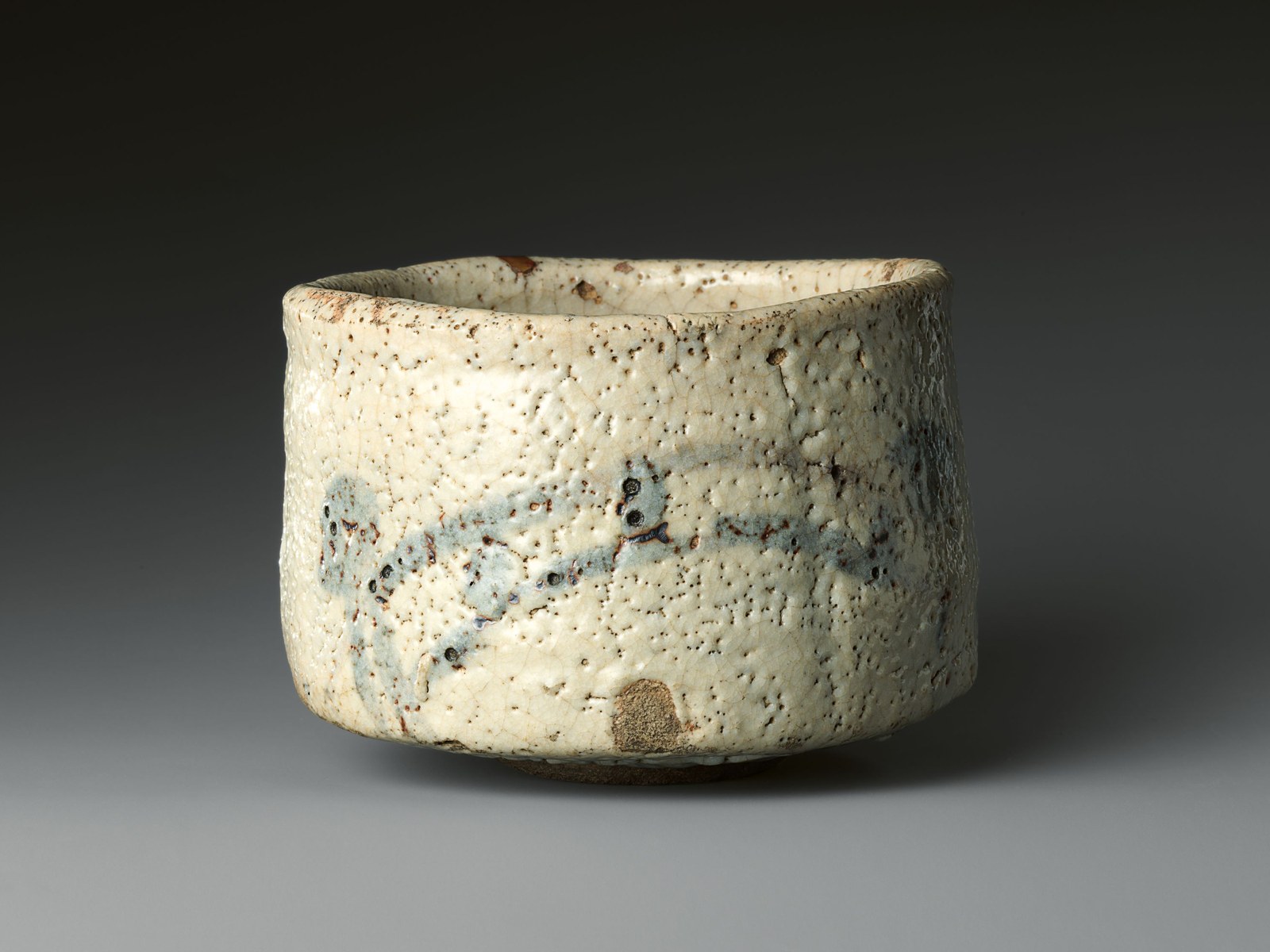 A straight-sided tea bowl in thick milky white Shino glaze, with faint painting showing beneath the glaze