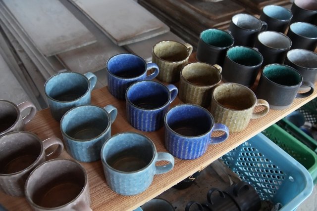 A row of everyday Mino ware mugs in different glaze colours — the modern production tableware the region makes in volume