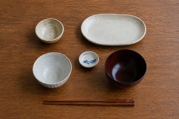 One person's set of empty Japanese vessels seen from above, arranged in the standard positions with a pair of chopsticks laid across the front
