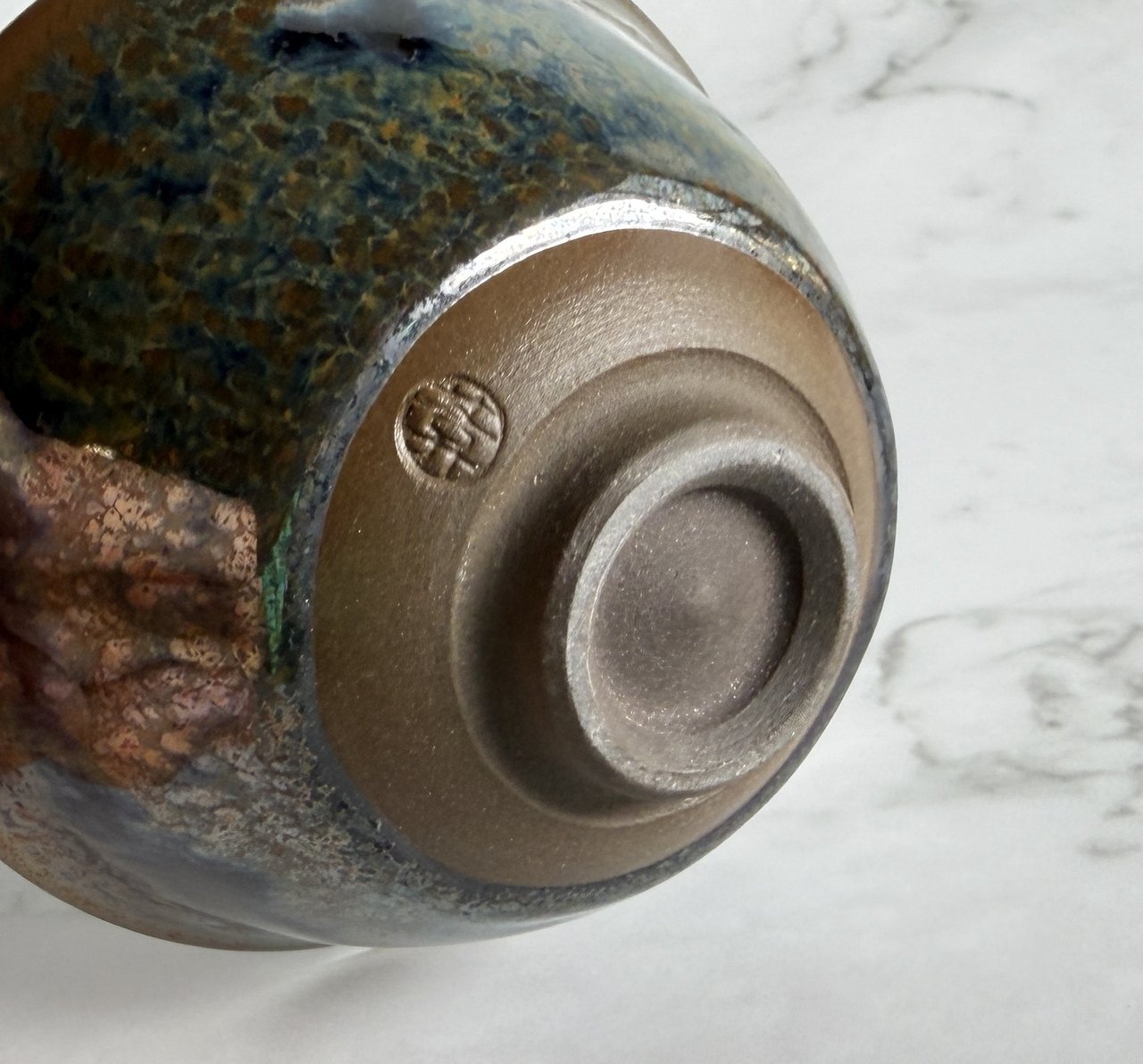 Close-up of the underside of a sake guinomi showing the kōdai foot ring with exposed unglazed clay — the window through which the kiln's true character can be read