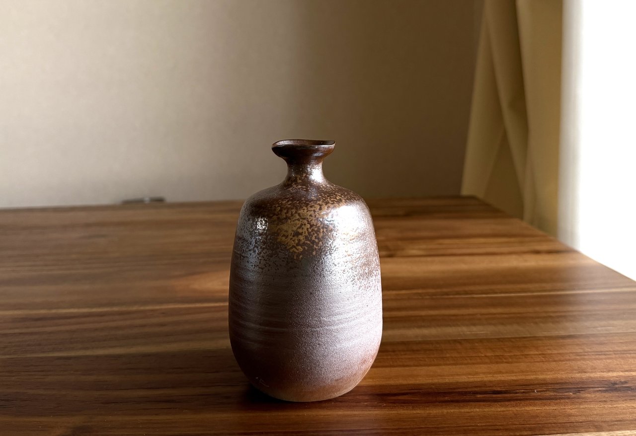 A Japanese tokkuri sake carafe with a narrow neck and rounded shoulder, the form designed to preserve warmth during the pour