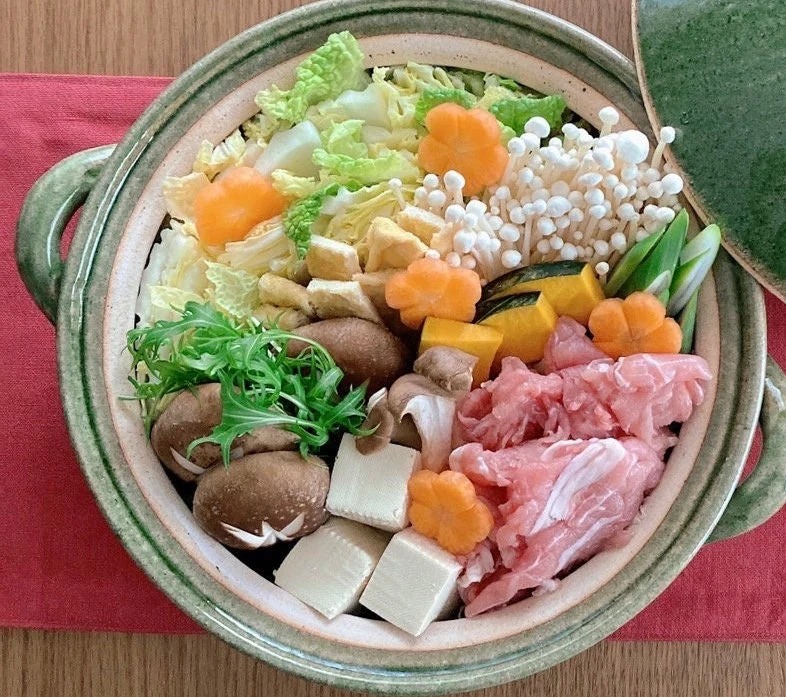 Vegetables, mushrooms, and thinly sliced meat arranged in a Shigaraki-ware donabe, ready for the table