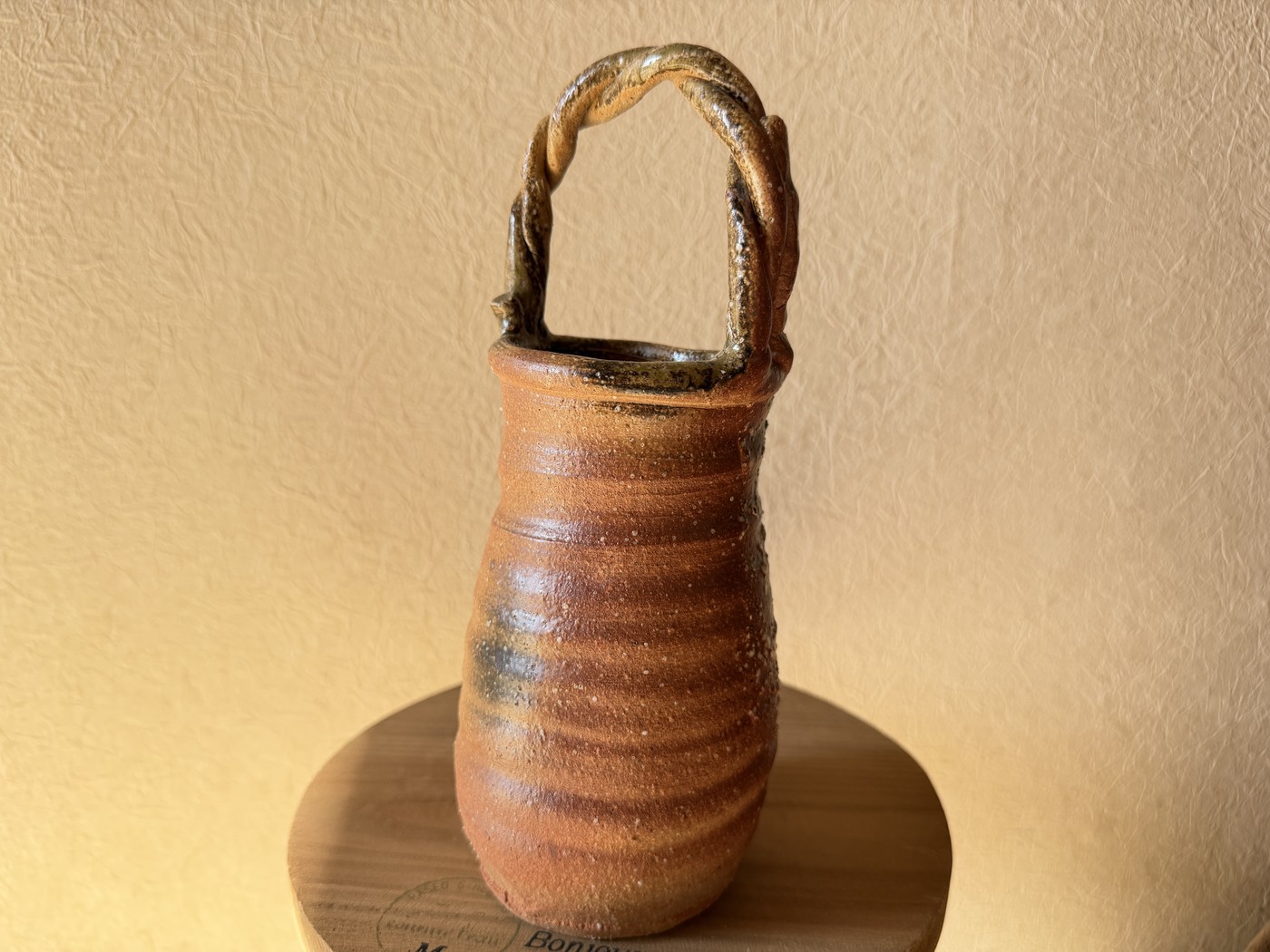 A tall Shigaraki-ware vase with a twisted handle and natural ash glaze