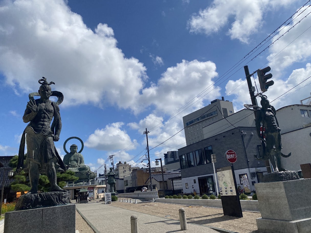 The Takaoka Daibutsu seen from the street, with cast bronze guardian figures nearby