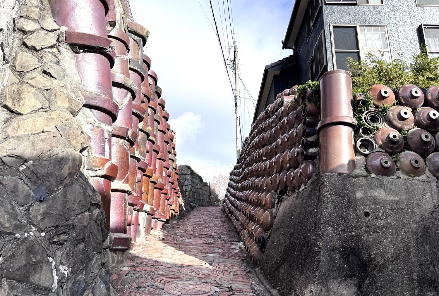 Dokanzaka, a narrow alley in Tokoname lined with old clay pipes and jars stacked into the walls