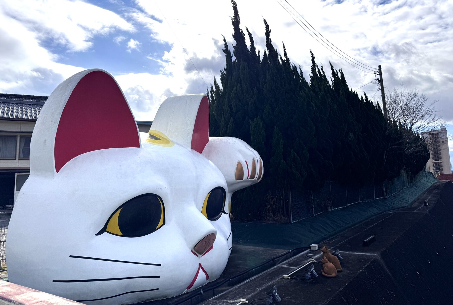 A large maneki-neko lucky cat mascot overlooking a street in Tokoname