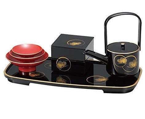 A black Yamanaka otoso set with gold pine motifs: a spouted server with a handle, three red nesting cups on a stand, a small tiered box, and the long tray they sit on