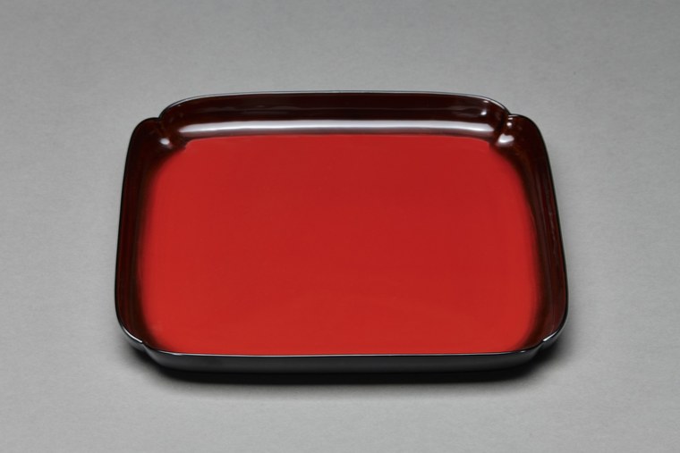 A square Yamanaka tray in deep glossy vermilion lacquer with a slightly raised rim, seen at an angle against a plain ground