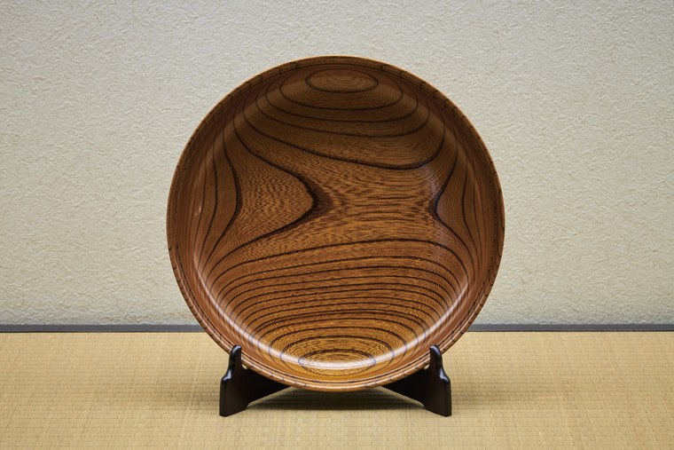 A wide turned wooden bowl from Yamanaka on a small stand, its grain sweeping across the inside of the bowl