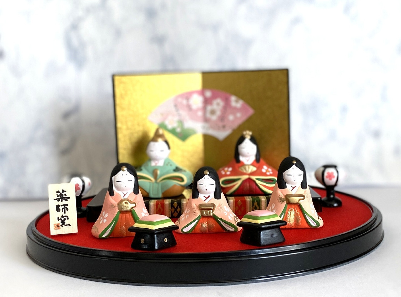 Seto-yaki Hinamatsuri doll set with multiple figures on a red platform, featuring a gold screen and festive accessories.